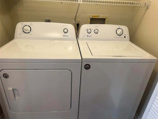 laundry room with a textured wall, laundry area, and washing machine and clothes dryer