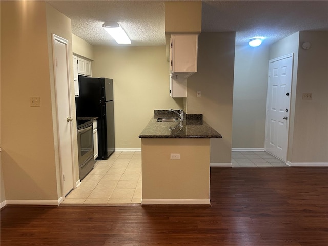 kitchen with stainless steel electric range oven, a textured ceiling, light wood-style floors, white cabinetry, and a sink