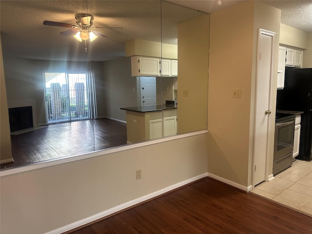 kitchen featuring dark countertops, electric range oven, light wood-style floors, white cabinets, and a textured ceiling