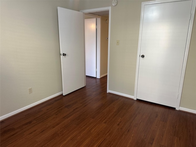 unfurnished bedroom featuring dark wood-type flooring and baseboards