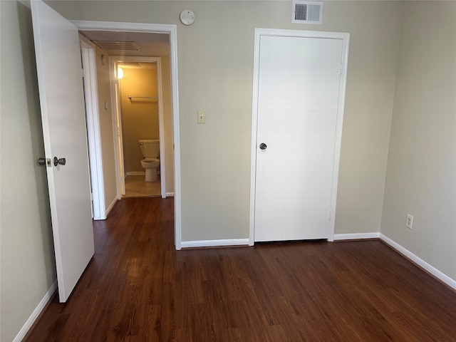 unfurnished bedroom with dark wood-style floors, visible vents, and baseboards