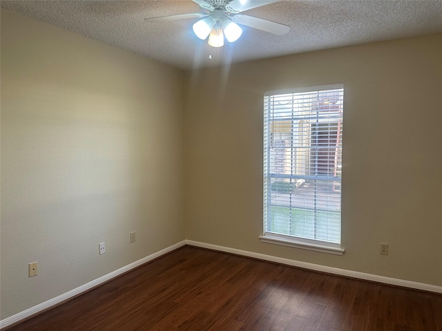 empty room with a wealth of natural light, ceiling fan, a textured ceiling, and dark wood-type flooring