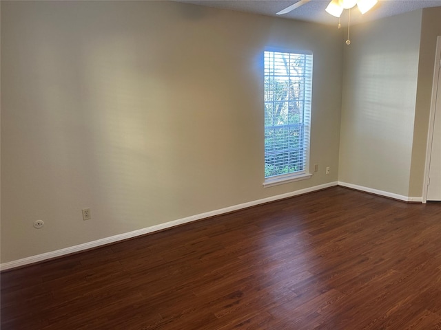 spare room featuring a ceiling fan, dark wood finished floors, and baseboards