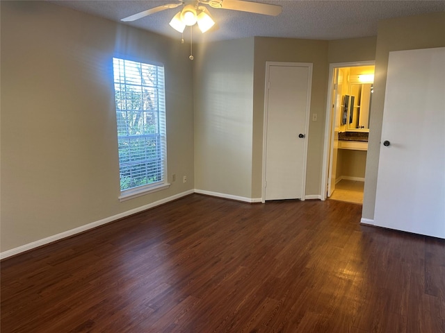 empty room with dark wood-style floors, ceiling fan, a textured ceiling, and baseboards