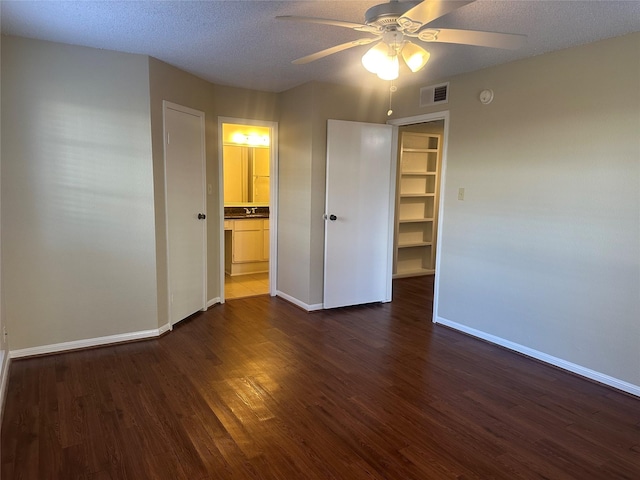 unfurnished bedroom featuring dark wood-type flooring, visible vents, a textured ceiling, and baseboards