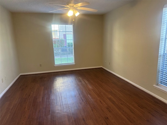 spare room with dark wood finished floors, a ceiling fan, and baseboards