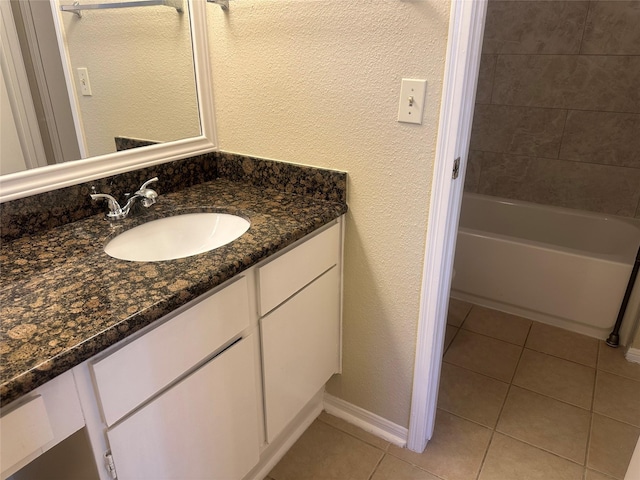 bathroom featuring a textured wall, tile patterned flooring, vanity, and baseboards