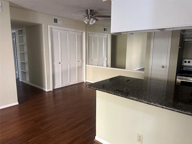 kitchen with dark wood-style flooring, stainless steel electric range oven, visible vents, ceiling fan, and a textured ceiling