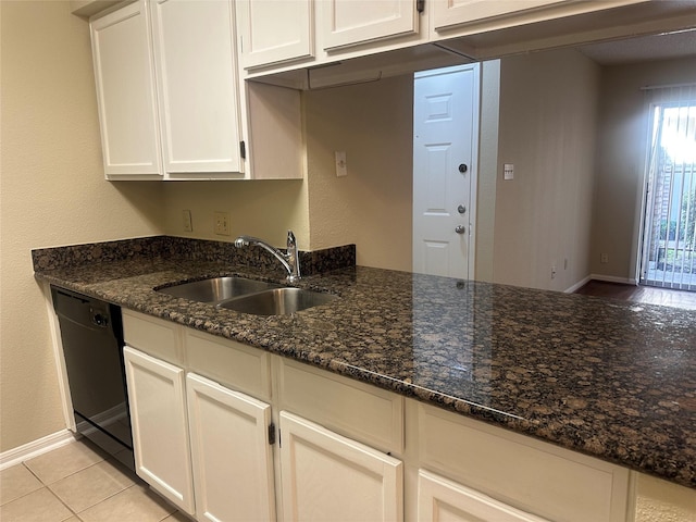 kitchen featuring dishwasher, dark stone countertops, a sink, and white cabinetry