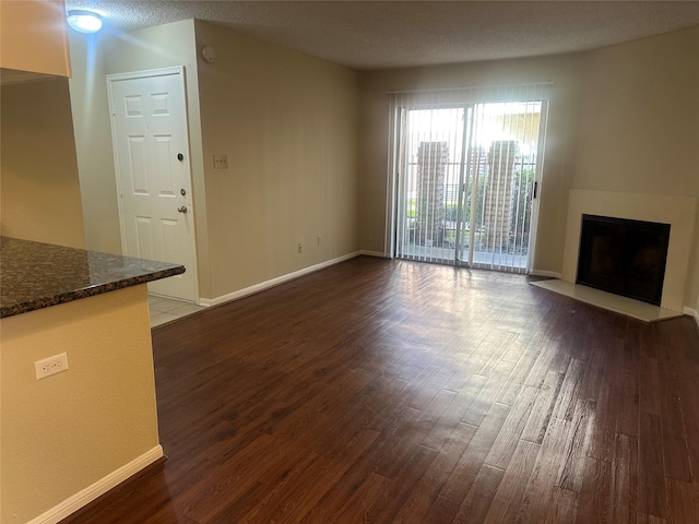 unfurnished living room featuring a fireplace, baseboards, and dark wood-type flooring