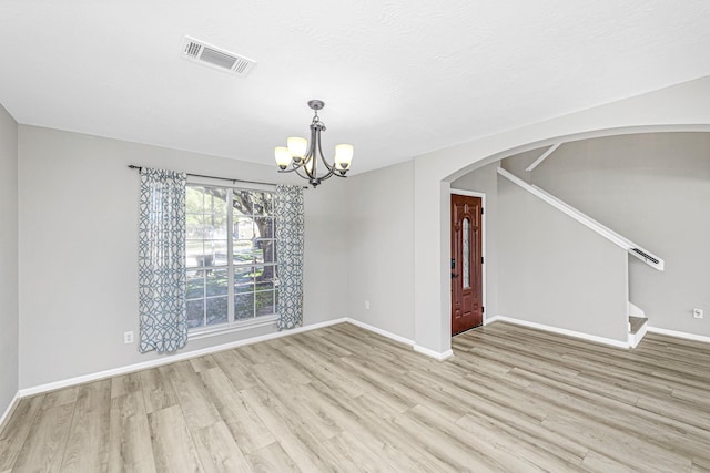 spare room with baseboards, visible vents, arched walkways, stairway, and wood finished floors