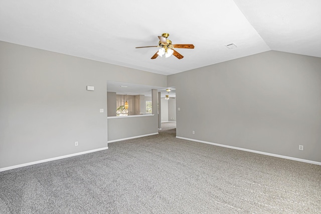 carpeted empty room with vaulted ceiling, a ceiling fan, and baseboards