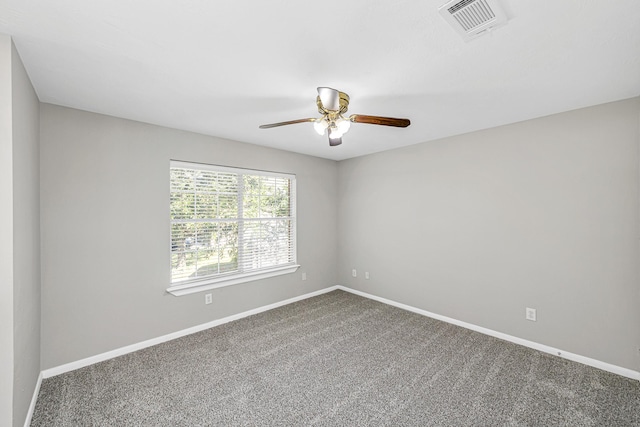 empty room with carpet floors, a ceiling fan, visible vents, and baseboards