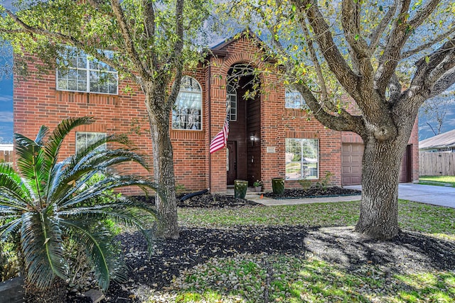 view of front of property featuring driveway, brick siding, an attached garage, and fence