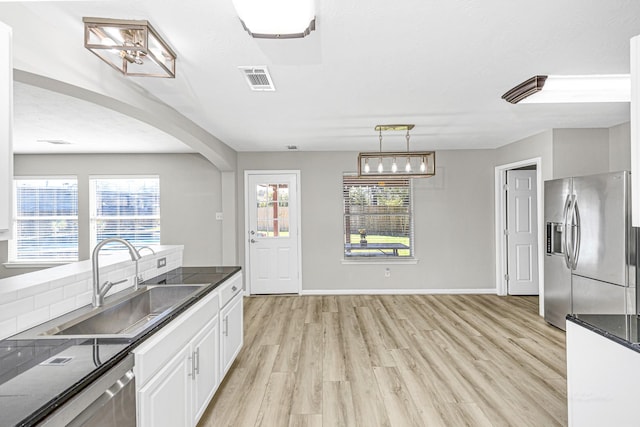 kitchen featuring visible vents, white cabinets, dark countertops, stainless steel appliances, and a sink