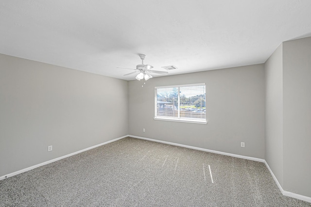 carpeted spare room featuring baseboards, visible vents, and ceiling fan