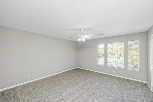 unfurnished room with carpet floors, visible vents, baseboards, and a ceiling fan