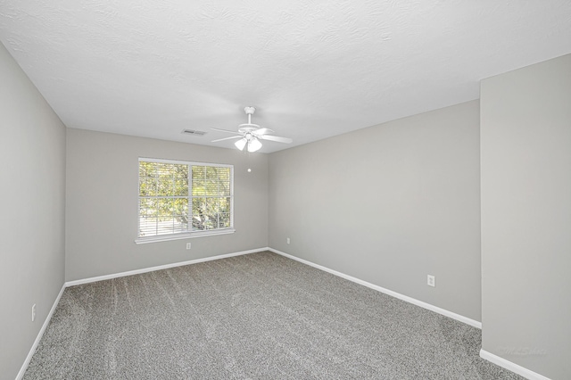 carpeted spare room with a textured ceiling, a ceiling fan, visible vents, and baseboards