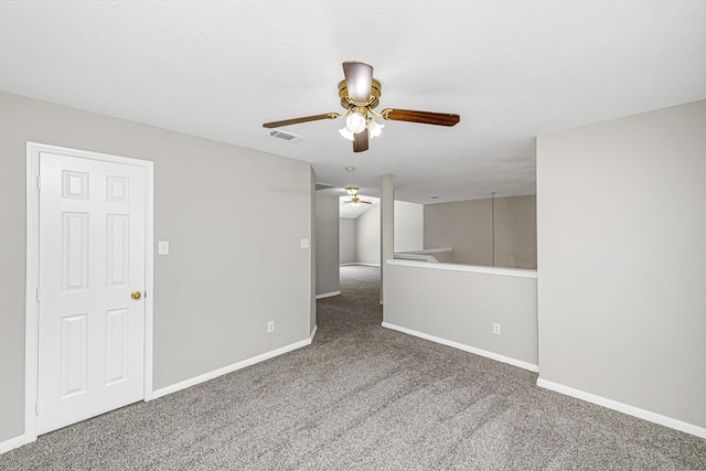 carpeted empty room featuring a ceiling fan, visible vents, and baseboards