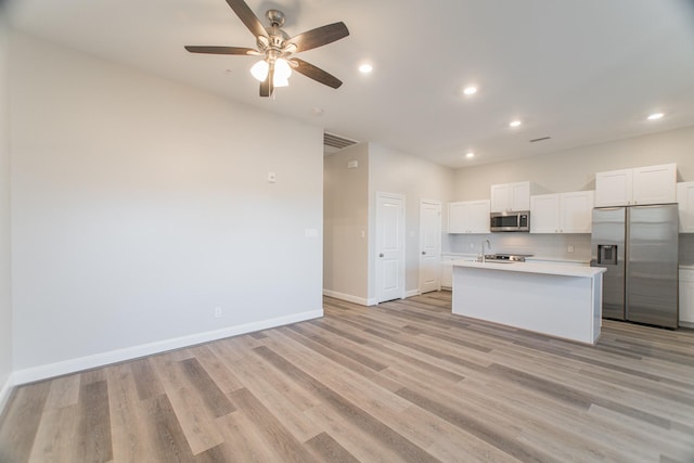 kitchen with light wood-style flooring, baseboards, white cabinets, light countertops, and appliances with stainless steel finishes