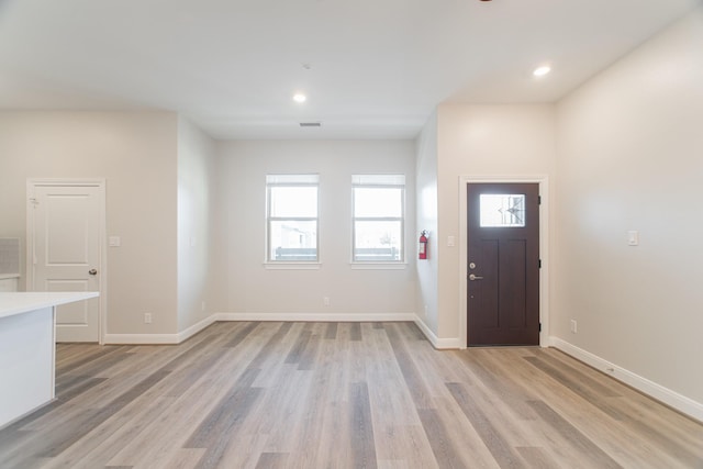 entrance foyer featuring light wood-type flooring, plenty of natural light, and baseboards