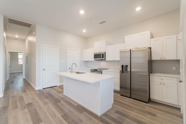 kitchen with visible vents, an island with sink, light wood-style flooring, appliances with stainless steel finishes, and a sink