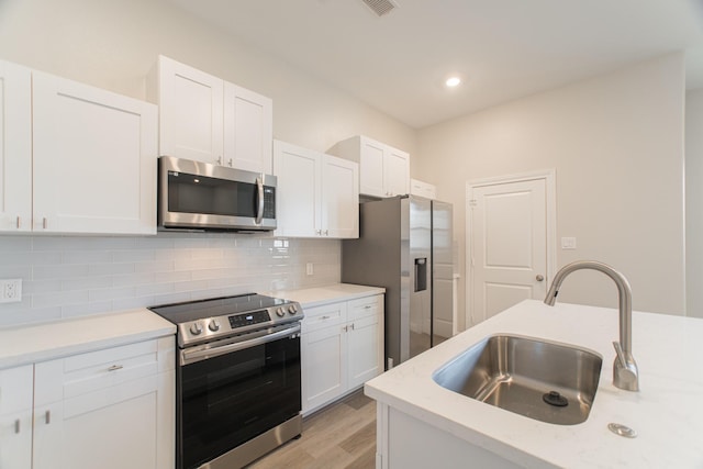 kitchen featuring appliances with stainless steel finishes, light countertops, a sink, and backsplash