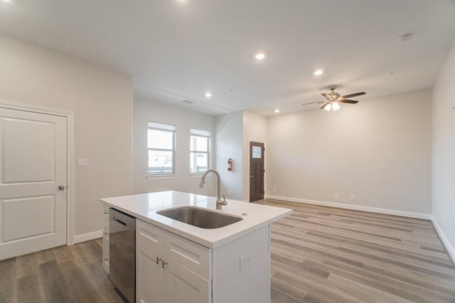 kitchen with a sink, light countertops, dishwasher, light wood finished floors, and an island with sink