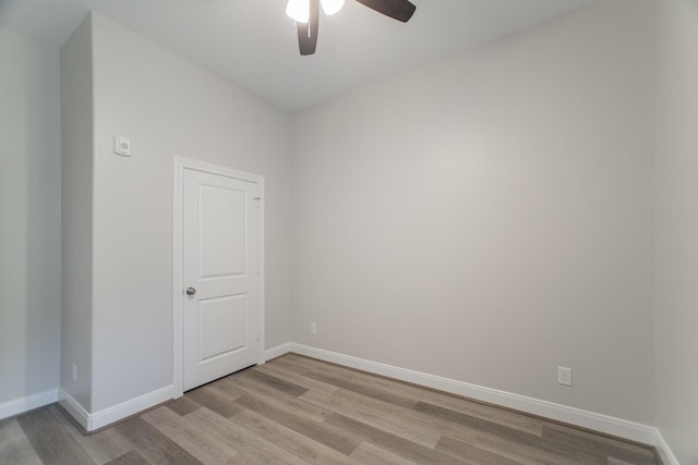 spare room featuring light wood finished floors, ceiling fan, and baseboards