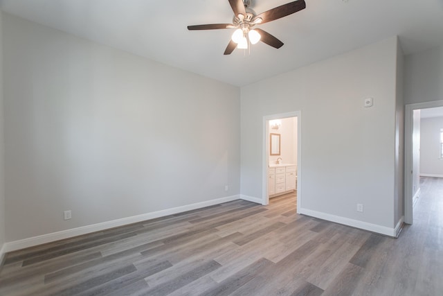 unfurnished bedroom with a ceiling fan, connected bathroom, baseboards, and wood finished floors