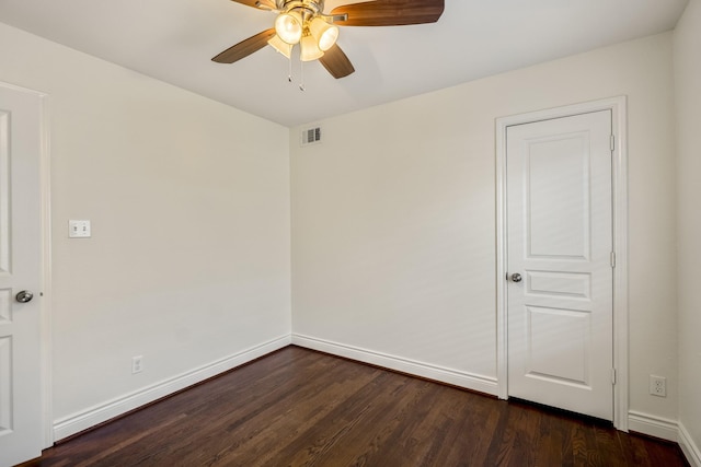 spare room with dark wood finished floors, visible vents, baseboards, and ceiling fan