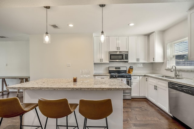 kitchen with visible vents, a center island, decorative backsplash, stainless steel appliances, and a sink