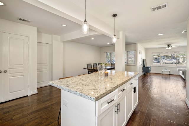 kitchen featuring visible vents, dark wood-type flooring, light stone countertops, open floor plan, and white cabinetry