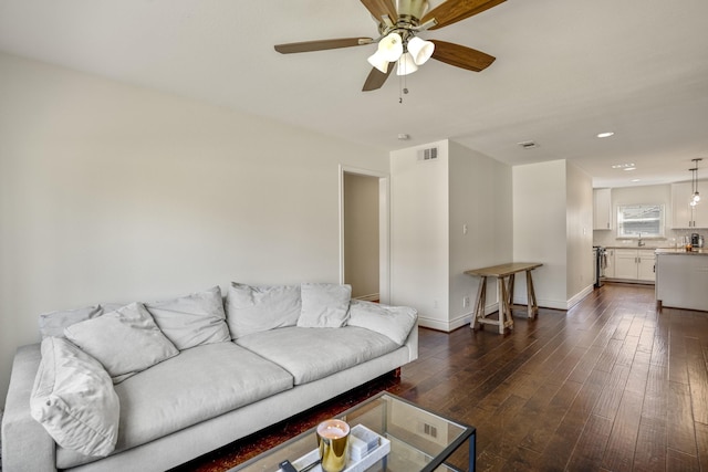 living room with dark wood-style floors, visible vents, ceiling fan, and baseboards