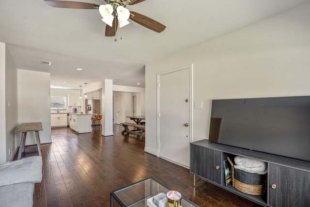 living area featuring visible vents, baseboards, recessed lighting, dark wood-style flooring, and ceiling fan