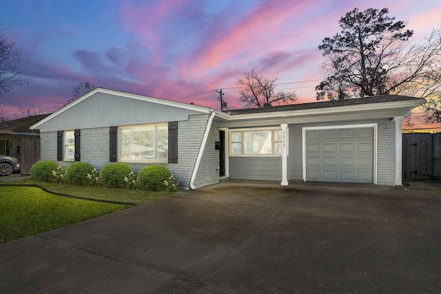 ranch-style house featuring a front lawn, brick siding, driveway, and fence