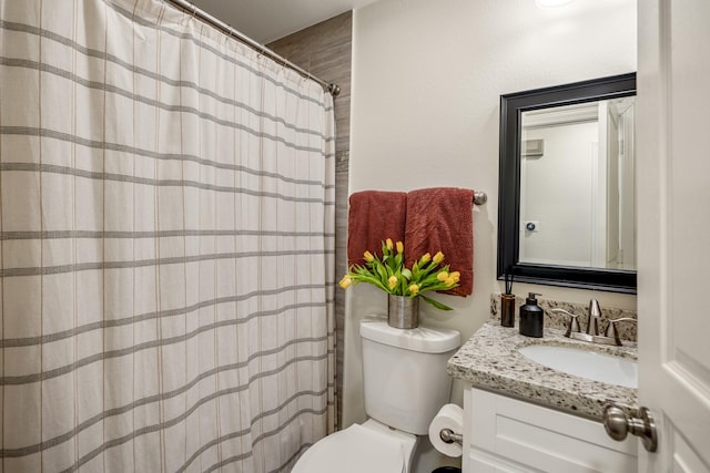 bathroom with curtained shower, toilet, and vanity