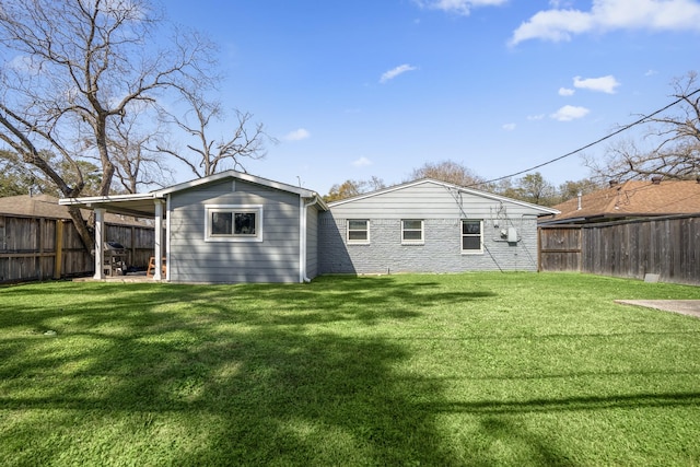 rear view of property featuring a lawn, brick siding, and a fenced backyard