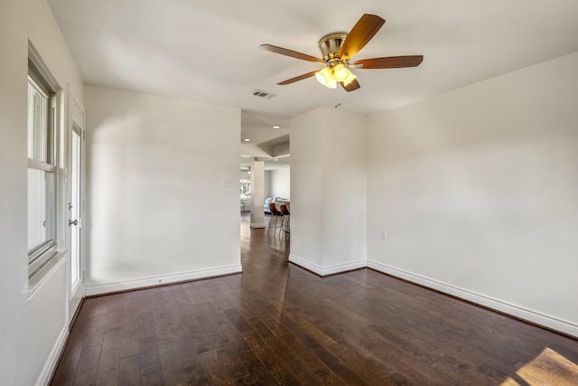 unfurnished room featuring visible vents, baseboards, dark wood-type flooring, and a ceiling fan