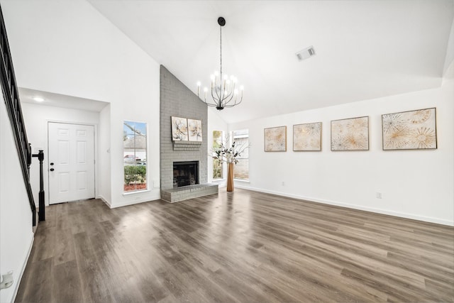 unfurnished living room with a brick fireplace, visible vents, baseboards, and wood finished floors