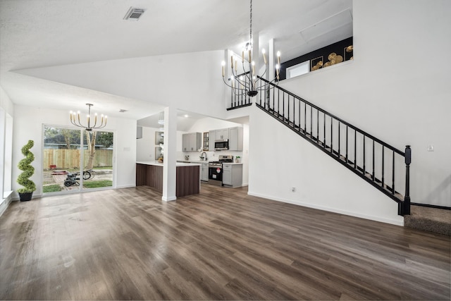 unfurnished living room with dark wood-style floors, visible vents, stairway, and a notable chandelier