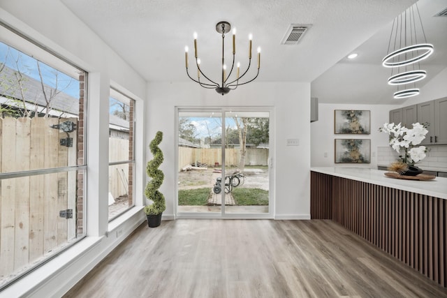 unfurnished dining area featuring light wood finished floors, visible vents, and a chandelier