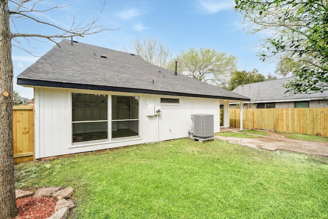 back of house with roof with shingles, fence, cooling unit, and a yard