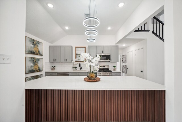 kitchen with a sink, stainless steel appliances, backsplash, and gray cabinets