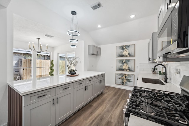 kitchen featuring decorative backsplash, dark wood-style flooring, stainless steel appliances, gray cabinetry, and a sink