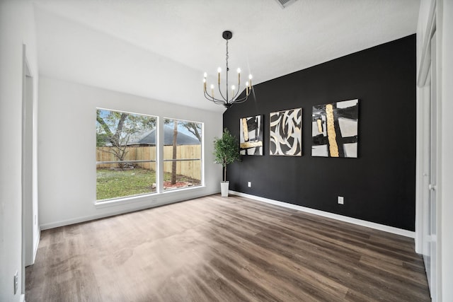 unfurnished dining area featuring an inviting chandelier, baseboards, and wood finished floors