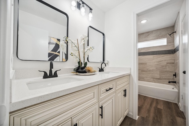 full bathroom with double vanity,  shower combination, wood finished floors, and a sink