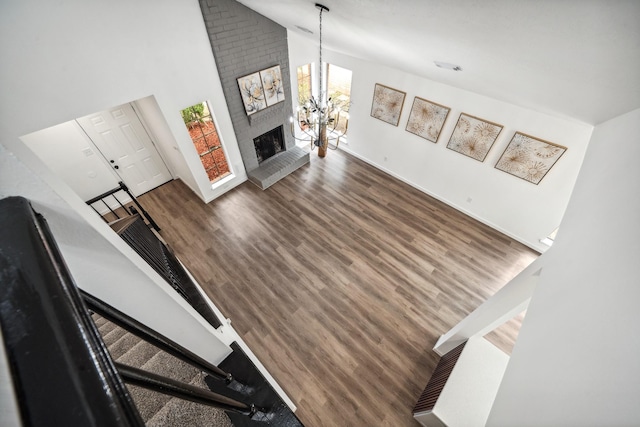 living area featuring a chandelier, wood finished floors, stairs, a fireplace, and high vaulted ceiling