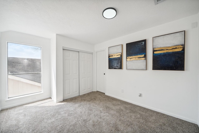 unfurnished bedroom featuring carpet floors, a closet, and baseboards