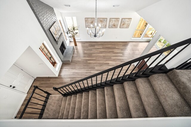 stairs featuring a chandelier, a fireplace, wood finished floors, visible vents, and vaulted ceiling